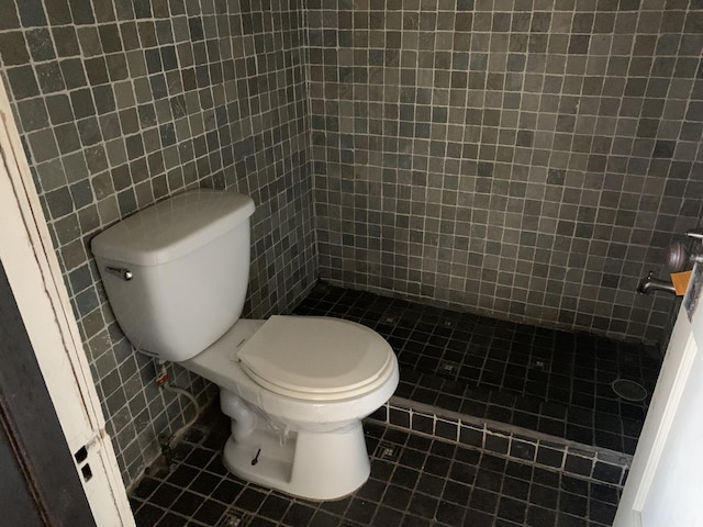 bathroom featuring tile patterned floors, toilet, walk in shower, and tile walls