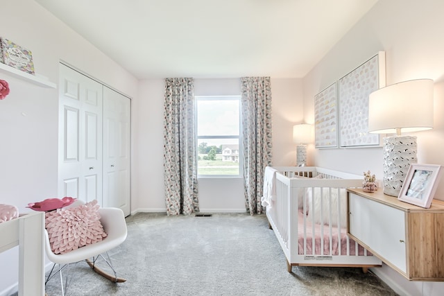 carpeted bedroom featuring a closet and a nursery area