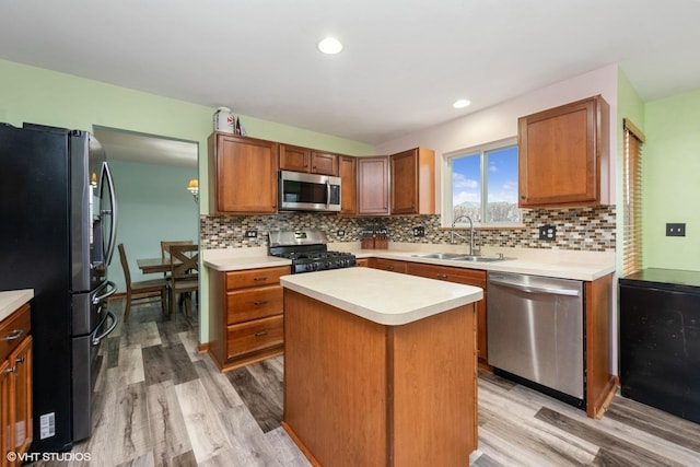 kitchen featuring stainless steel appliances, light hardwood / wood-style floors, sink, and a kitchen island