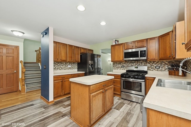 kitchen with a kitchen island, appliances with stainless steel finishes, sink, backsplash, and light hardwood / wood-style floors