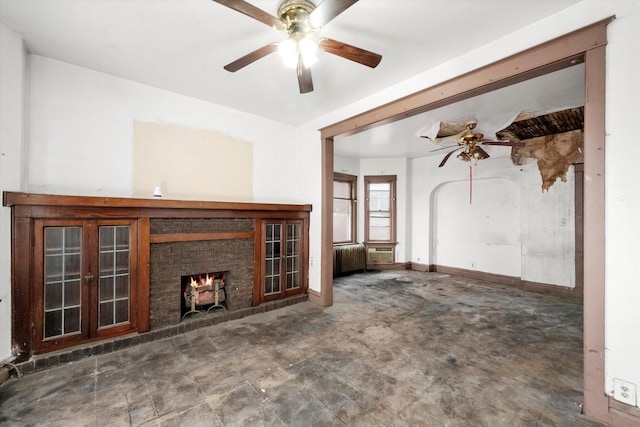 unfurnished living room featuring a fireplace, radiator, and ceiling fan