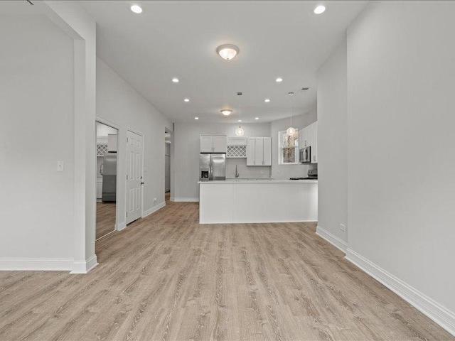 kitchen with white cabinets, pendant lighting, light wood-type flooring, and stainless steel appliances