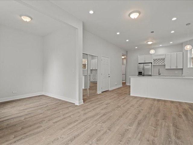 unfurnished living room featuring light wood-type flooring and sink