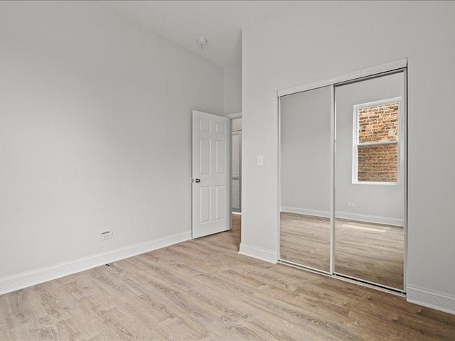 unfurnished bedroom with light hardwood / wood-style flooring and a closet