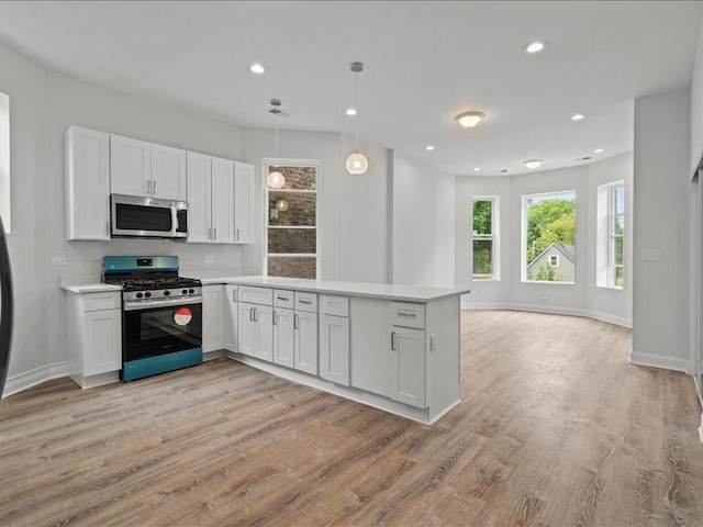 kitchen featuring pendant lighting, white cabinetry, kitchen peninsula, and appliances with stainless steel finishes