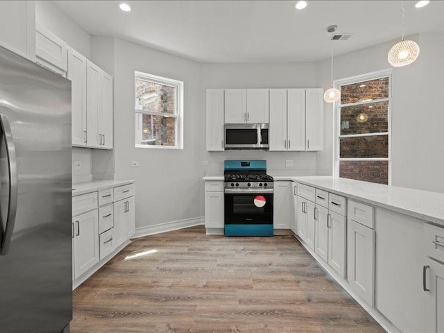 kitchen with white cabinets, pendant lighting, and stainless steel appliances