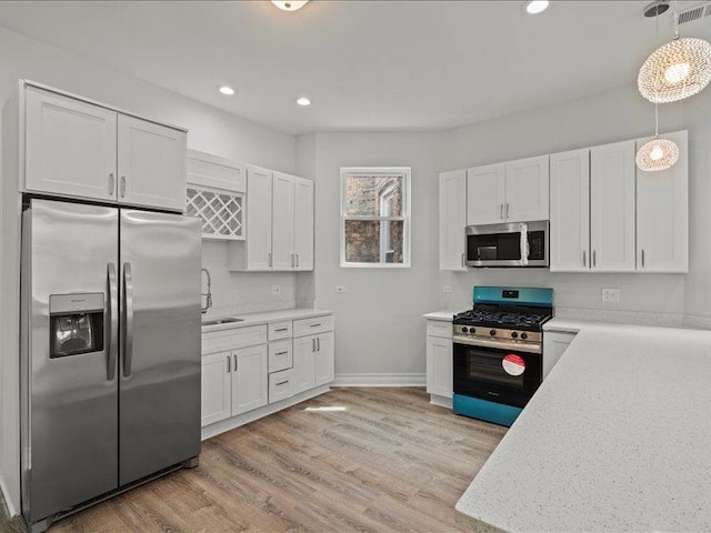 kitchen featuring white cabinets, stainless steel appliances, decorative light fixtures, and light wood-type flooring