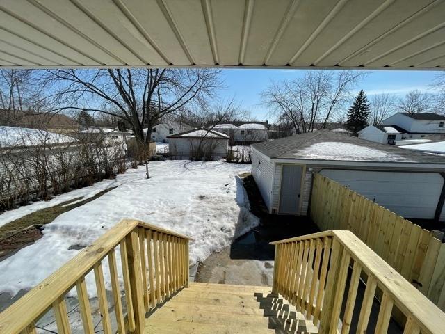 yard covered in snow with a detached garage and fence