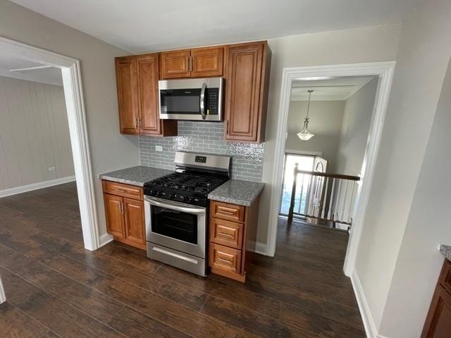 kitchen featuring brown cabinetry, dark wood-style flooring, stainless steel appliances, and backsplash