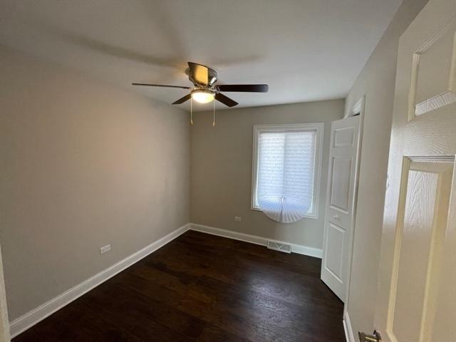 unfurnished bedroom featuring dark wood-type flooring, a ceiling fan, visible vents, and baseboards