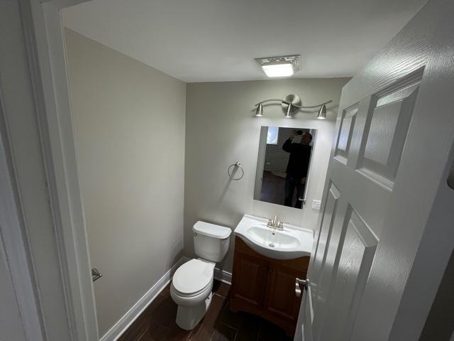 bathroom with toilet, baseboards, wood finished floors, and vanity