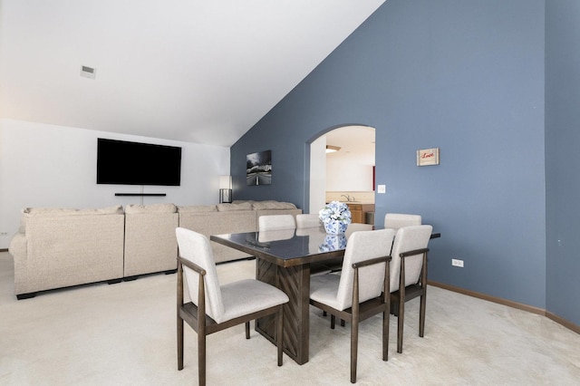 carpeted dining space featuring high vaulted ceiling