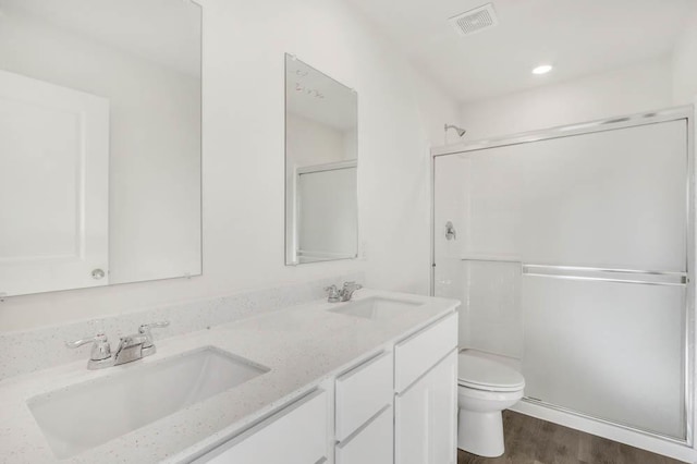 bathroom with hardwood / wood-style floors, vanity, toilet, and an enclosed shower