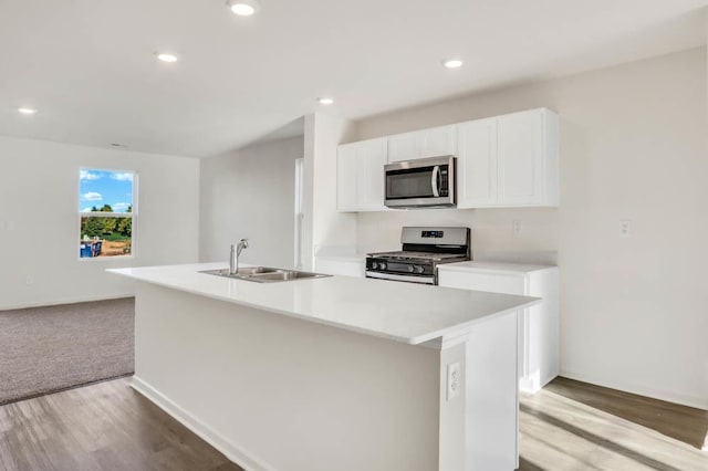 kitchen with white cabinetry, sink, stainless steel appliances, a center island with sink, and light wood-type flooring