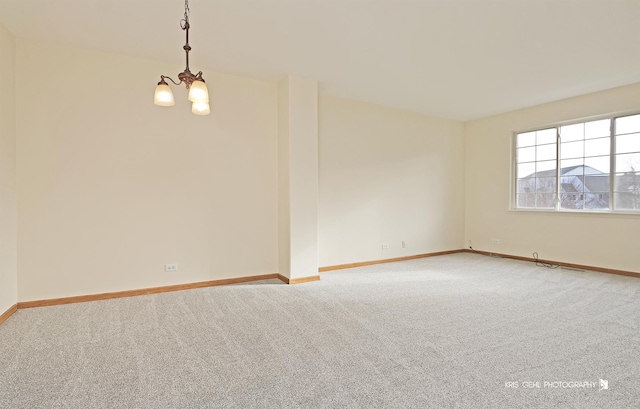 carpeted empty room featuring a notable chandelier