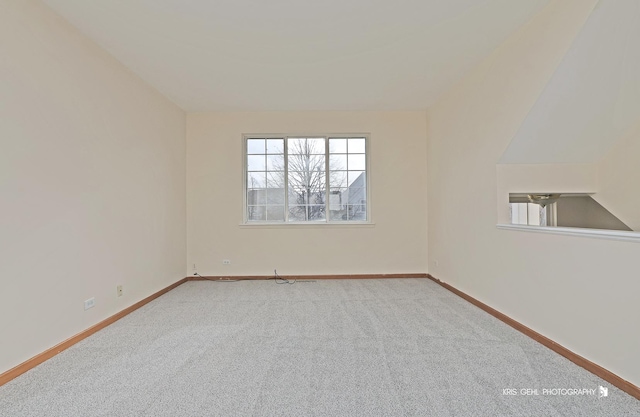 empty room featuring carpet and vaulted ceiling