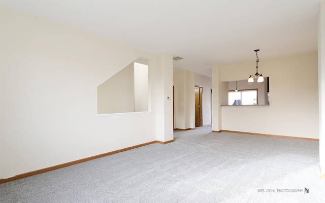 carpeted empty room featuring a chandelier