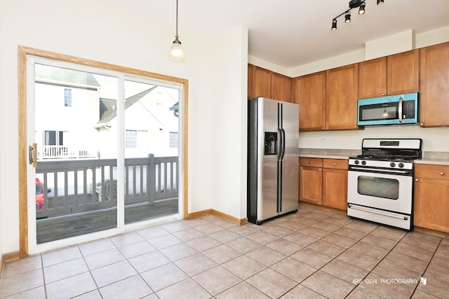 kitchen featuring appliances with stainless steel finishes, light tile patterned floors, and hanging light fixtures