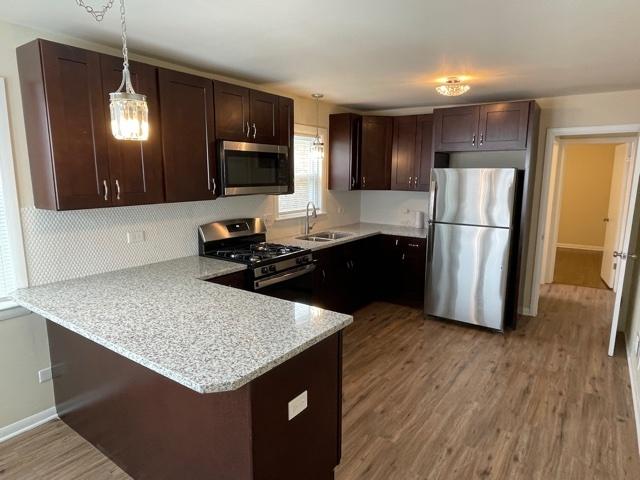 kitchen with stainless steel appliances, pendant lighting, a sink, and a peninsula