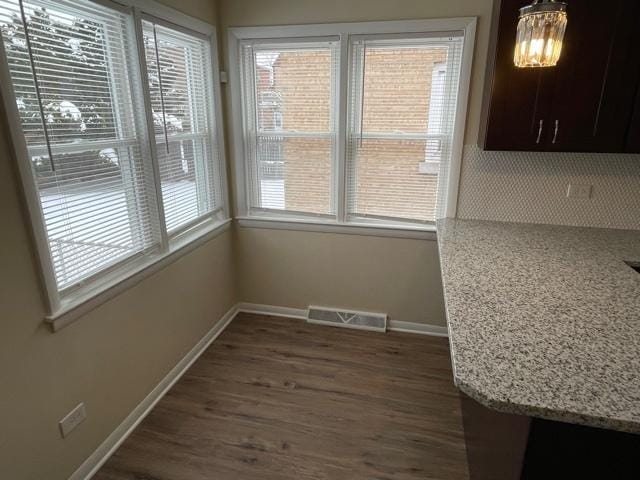 unfurnished dining area with dark wood-type flooring, visible vents, and baseboards