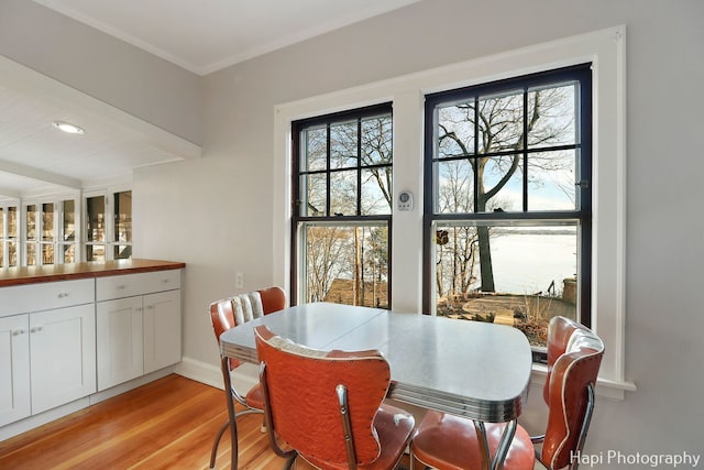 dining space featuring crown molding and light hardwood / wood-style flooring