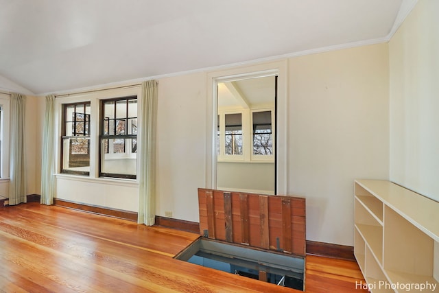 unfurnished room featuring light hardwood / wood-style floors, ornamental molding, and vaulted ceiling