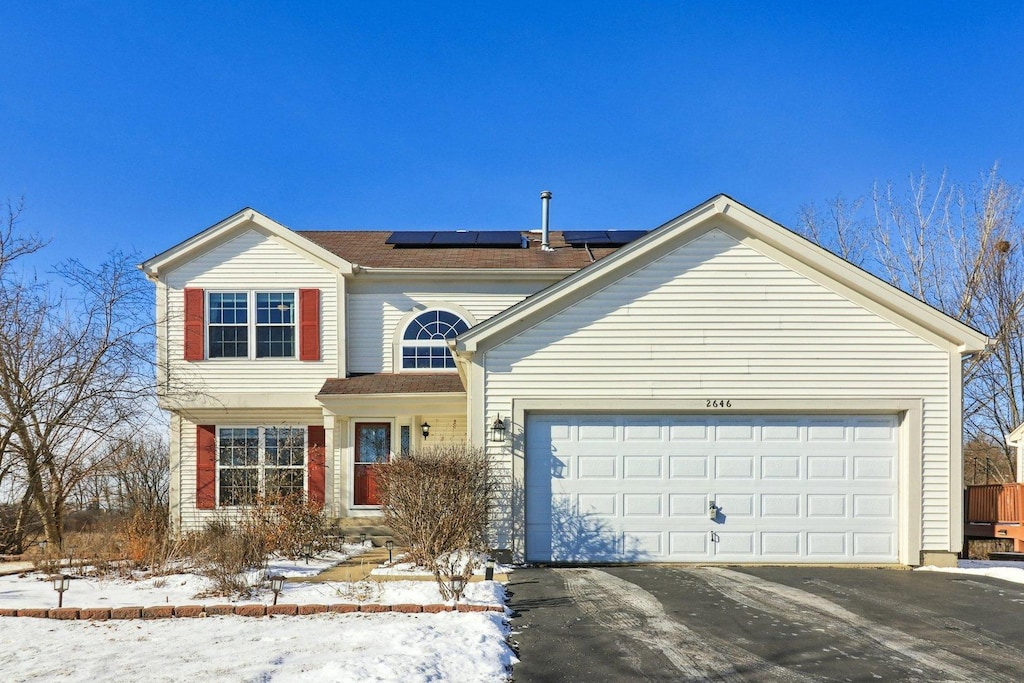 view of front property with a garage and solar panels