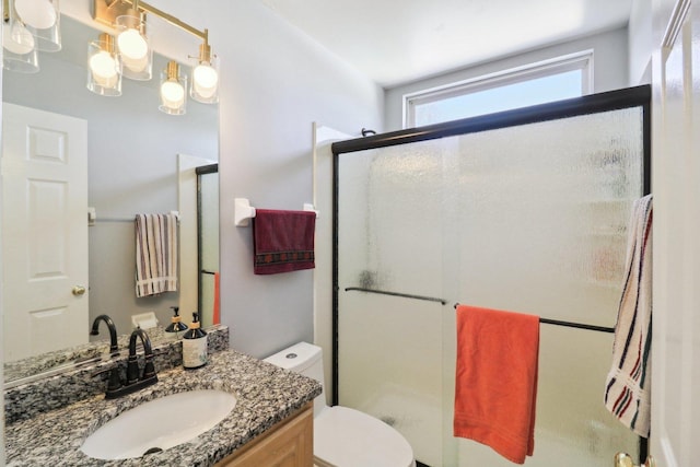 bathroom featuring vanity, toilet, and a shower with shower door