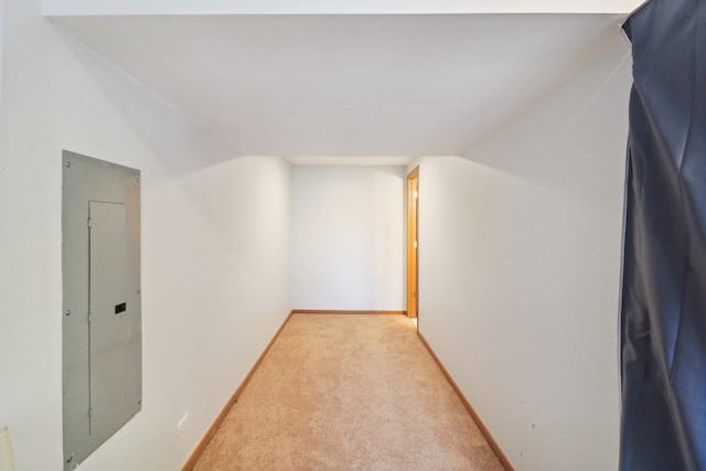 corridor featuring vaulted ceiling, light colored carpet, and electric panel