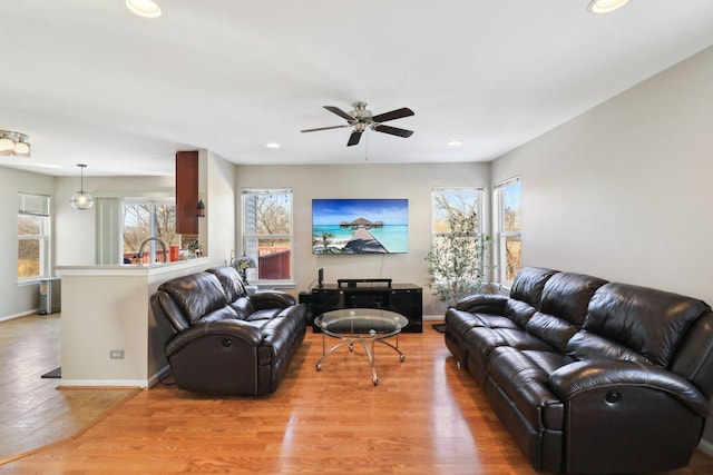 living room with ceiling fan, a wealth of natural light, and light hardwood / wood-style floors