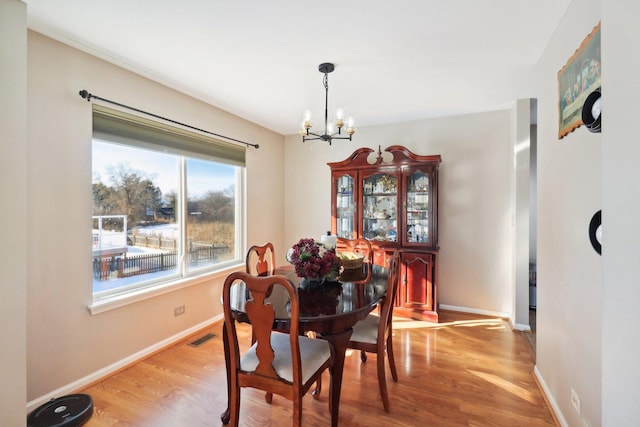 dining space with hardwood / wood-style flooring and a chandelier