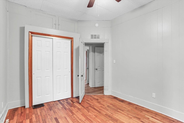 unfurnished bedroom featuring ceiling fan, light wood-type flooring, and a closet