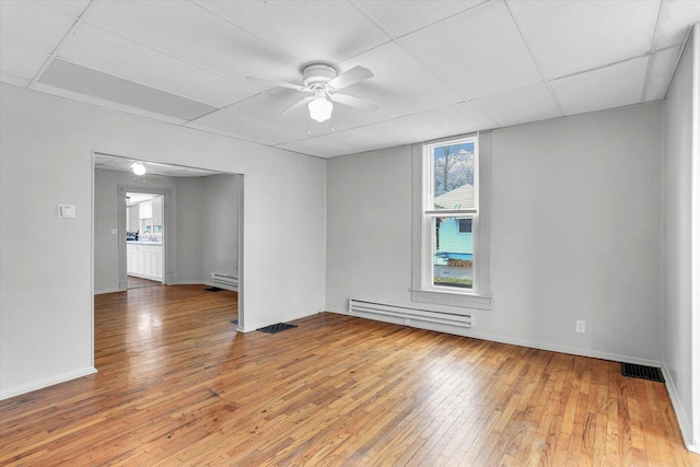 empty room featuring hardwood / wood-style flooring, a drop ceiling, and baseboard heating