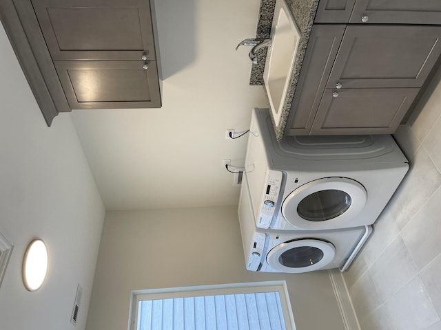 laundry room with cabinets and stacked washer / drying machine