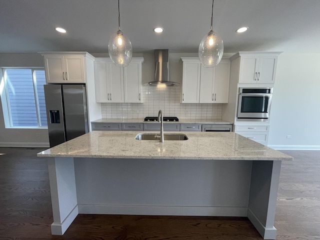 kitchen with appliances with stainless steel finishes, decorative light fixtures, white cabinetry, and wall chimney exhaust hood