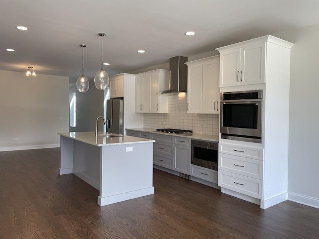 kitchen with a kitchen island with sink, white cabinets, wall chimney exhaust hood, dark hardwood / wood-style floors, and stainless steel appliances