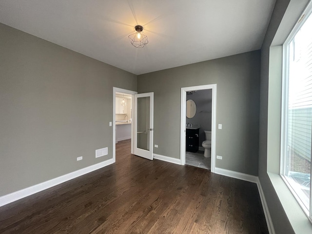 unfurnished bedroom featuring connected bathroom and dark hardwood / wood-style flooring