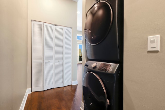 washroom featuring dark wood-type flooring and stacked washer / dryer