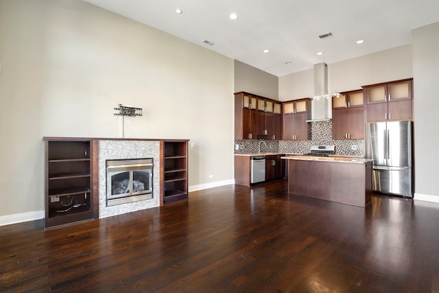 kitchen featuring wall chimney range hood, dark hardwood / wood-style floors, a center island, and stainless steel appliances