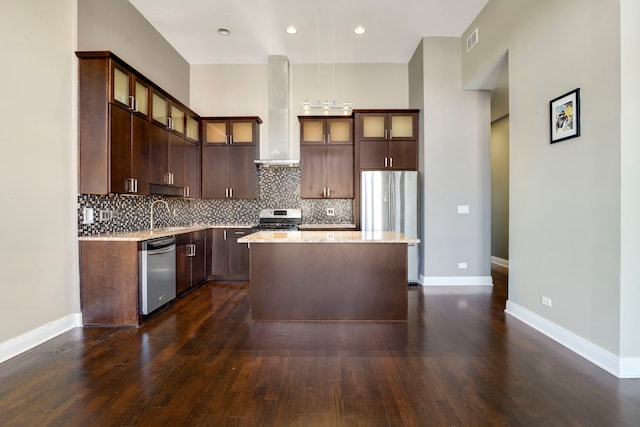 kitchen with stainless steel appliances, dark hardwood / wood-style flooring, light stone countertops, wall chimney exhaust hood, and a center island