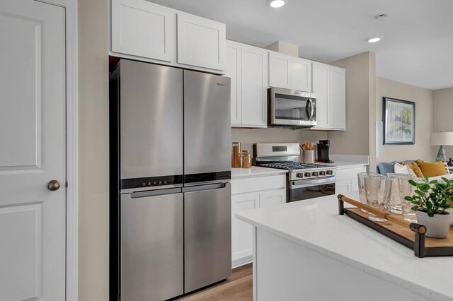 kitchen featuring light hardwood / wood-style flooring, white cabinets, and appliances with stainless steel finishes