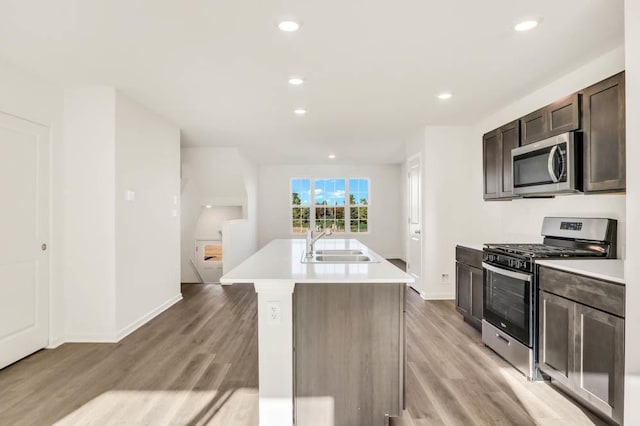 kitchen featuring appliances with stainless steel finishes, light hardwood / wood-style floors, a kitchen island with sink, and sink