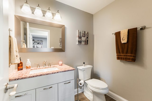 bathroom with vanity, toilet, and hardwood / wood-style floors