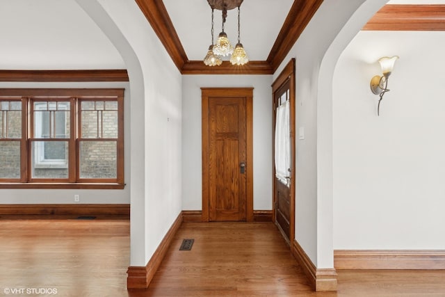 entryway with a chandelier, crown molding, and light hardwood / wood-style floors