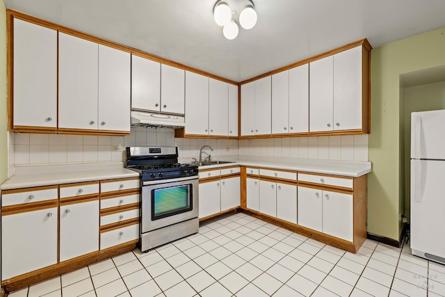 kitchen featuring gas stove, white cabinetry, tasteful backsplash, and white fridge