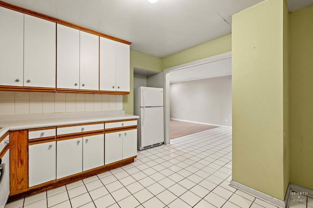 kitchen featuring white cabinets, light tile patterned floors, white refrigerator, and backsplash