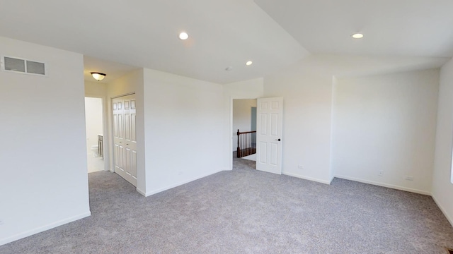 carpeted spare room with lofted ceiling