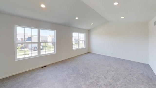 carpeted spare room with vaulted ceiling