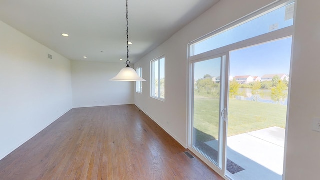 unfurnished dining area featuring hardwood / wood-style flooring and a water view