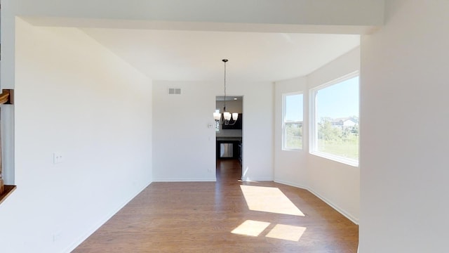 unfurnished dining area featuring hardwood / wood-style floors and a chandelier